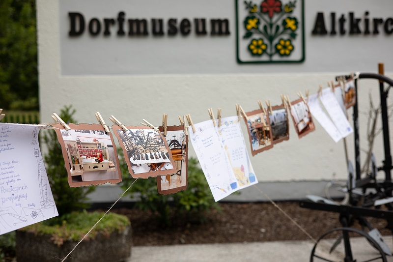 Altkirchen. Vor dem Dorfmuseum sind diverse Aufzeichnungen und farbige Fotomotive mit kleinen Holzwäscheklammern auf einer Leine aufgehängt. Die Bilderreihe gibt einige Hinweise für die Besucher, was sie in der Führung erwartet.