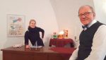Museumsmitarbeiterin Franziska Huberty hinter dem Tresen, Bernd Adam zum Videointerview davor.